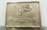 Brass plaque with 'Rose Cottage' and a rose design on a white background